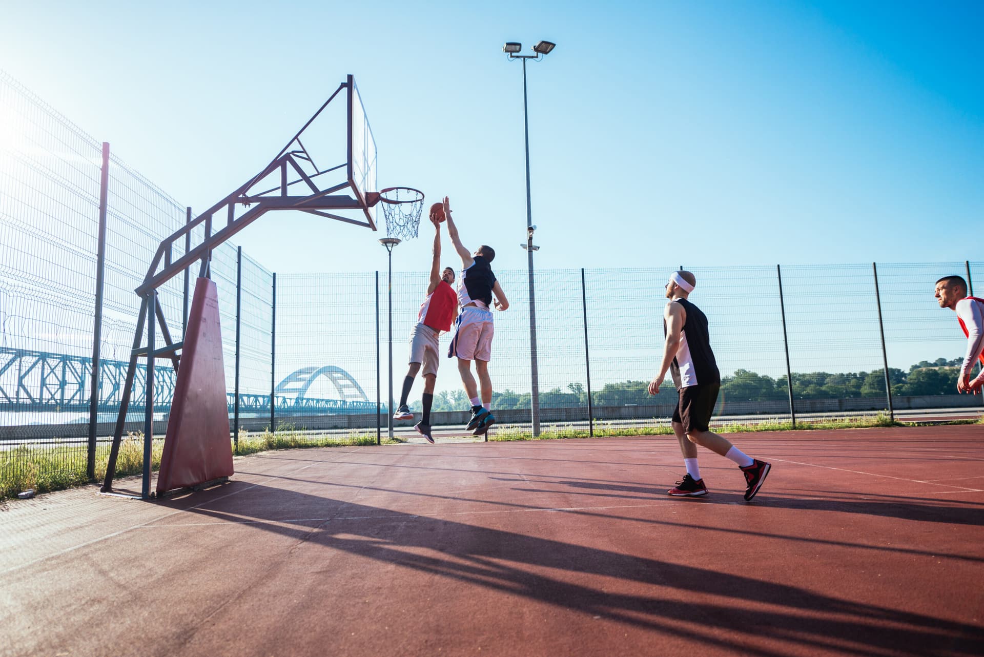 Basketball players jumping on outdoor court in the sun